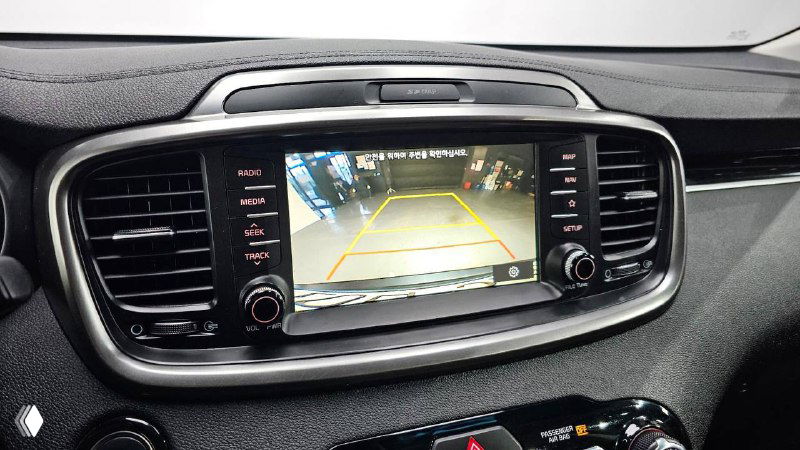 Фотография мультимедийной панели и экрана заднего вида KIA Sorento 2018, показаны линии парковки и центральная консоль автомобиля в салоне