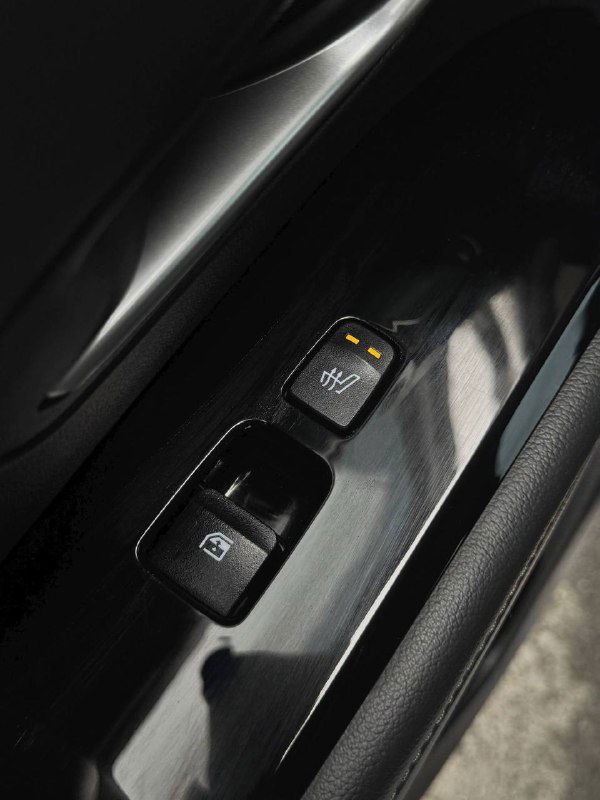 Крупный план панели двери с кнопками управления стеклами и переключателем подогрева, глянец и текстура отделки вблизи ручки двери Hyundai Tucson.