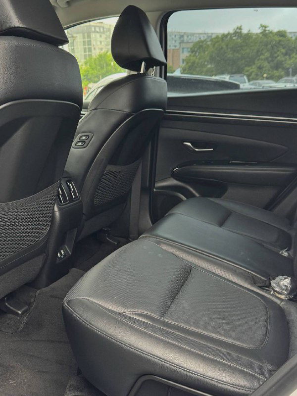 Вид на задние сиденья Hyundai Tucson — чёрная кожаная обивка, запас места для ног и состояние заднего ряда, выполнено в городских условиях парковки.