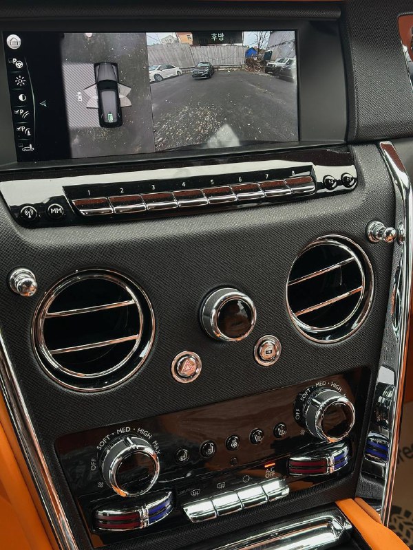 Центральная панель и экран мультимедиа в Rolls‑Royce Cullinan: воздуховоды, карбоновые вставки и хромированные регуляторы крупным планом.