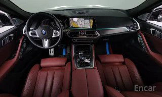 Интерьер BMW X6 xDrive 40i M‑Sport 2021: торпедо и руль, вид салона с красной кожей, мультимедиа‑экран и навигация, просторная передняя зона.