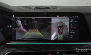 Экран мультимедиа BMW X6 показывает камеру заднего вида и панорамное изображение сверху для помощи при парковке, интерфейс системы и разметка траектории.