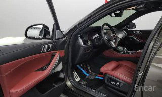 Открытая водительская дверь BMW X6 2021, вид на сиденье и внутреннюю отделку красной кожи, видны регулировки сиденья и порог, салон в хорошем состоянии.