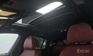 Вид на панорамную крышу и передние/задние сиденья BMW X6 xDrive 40i M‑Sport: большой люк, световой поток, красная кожа сидений и контрастная отделка потолка.