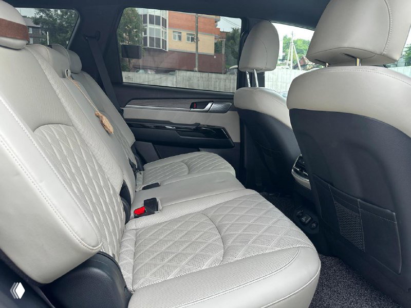 Задний ряд сидений Kia Mohave: белая кожаная обивка, три посадочных места и пространство для ног — фото интерьера автомобиля на продаже.