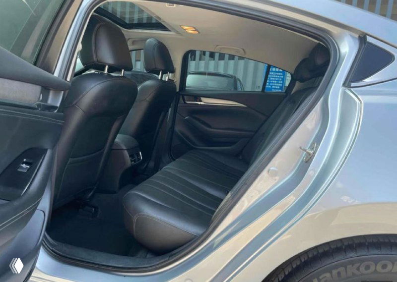 Задний ряд сидений Mazda Atenza с кожаной обивкой, открытая задняя дверь показывает пространство для ног и состояние заднего салона автомобиля