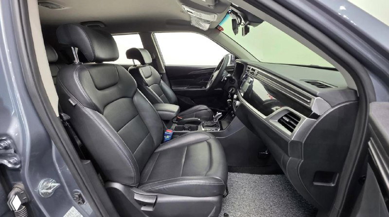 Вид на передние сиденья Ssangyong Korando 2020 с открытой дверью: чёрная кожаная обивка, подголовники и пространство для ног спереди.