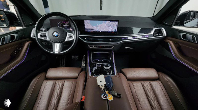 Интерьер BMW X5 с коричневой кожей, панель приборов, руль и центральный дисплей, крупный план салона и приборной панели.