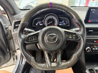 Крупный план рулевого колеса Mazda CX‑4 с леерной накладкой и кнопками управления — видно спидометр и элементы управления на руле в деталях.