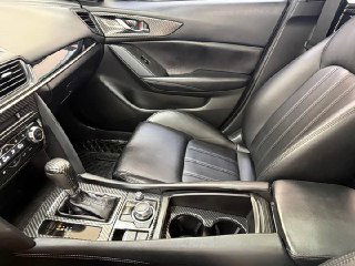 Переднее пассажирское и водительское сиденья Mazda CX‑4 — чёрная кожаная отделка, вид боковой панели и подлокотника, состояние салона вблизи.