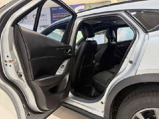 Задние двери Mazda CX‑4 открыты, вид на задний ряд сидений — чёрная обивка, пространство для пассажиров и состояние заднего салона.