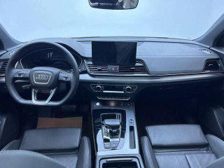 Салон Audi Q5L 2022: вид на рулевую колонку, центральную консоль и приборную панель — чёрная отделка и мультимедиа экран спереди.