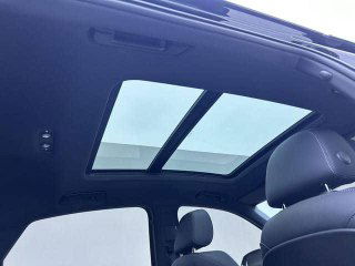 Панорамная крыша Audi Q5L Sportback: крупный вид застеклённого люка и естественного освещения в салоне автомобиля чёрного цвета.