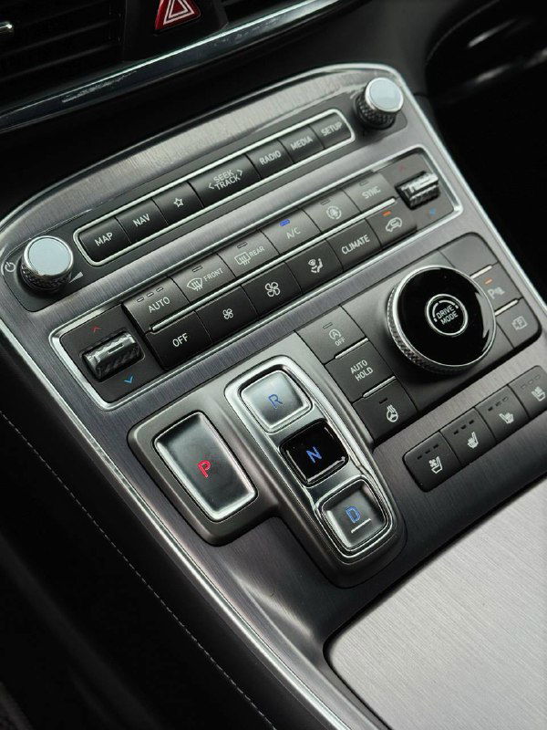 Крупный план блока управления центральной консоли Hyundai Santa Fe 2022 — селектор передач, кнопки климат-контроля и мультимедийные органы управления в комплектации Calligraphy.