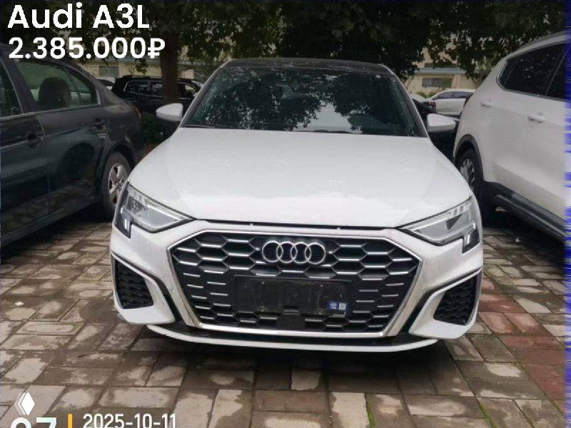 Белый Audi A3L на стоянке, вид спереди, крупный план решетки радиатора и фары, цена 2.385.000₽ указана на изображении.