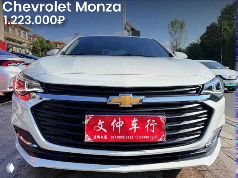 Серебристый Chevrolet Monza, вид спереди на парковке, номерная табличка на фото, цена 1.223.000₽ указана как вариант из Китая.