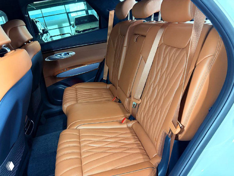 Задний ряд сидений Genesis GV70 2023 — коричневая кожаная отделка, ремни безопасности и раскрой обивки, фото показывает состояние заднего салона