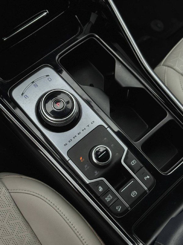 Центральная консоль и селектор передач KIA Sorento — вид на шайбу коробки передач, подстаканники и глянцевую отделку.