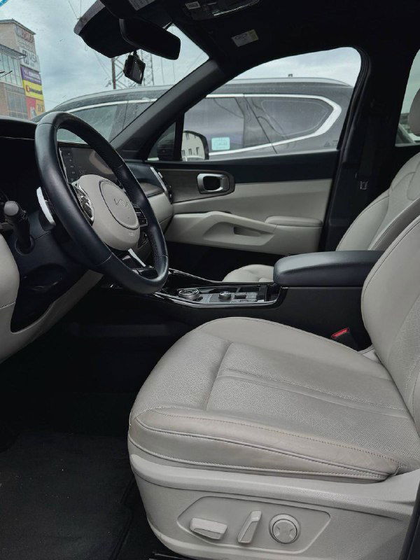 Вид салона KIA Sorento с места водителя — кресло, руль и центральный тоннель, демонстрируется состояние отделки и посадки.