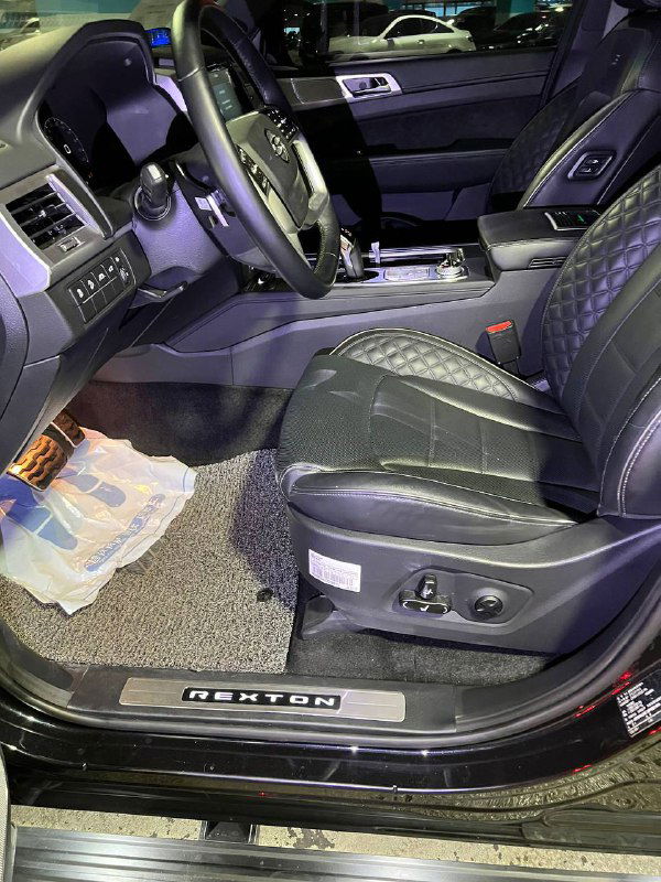 Водительское сиденье SsangYong Rexton с простроченной кожаной обивкой, электрорегулировками и порогом с надписью REXTON — детальный вид.