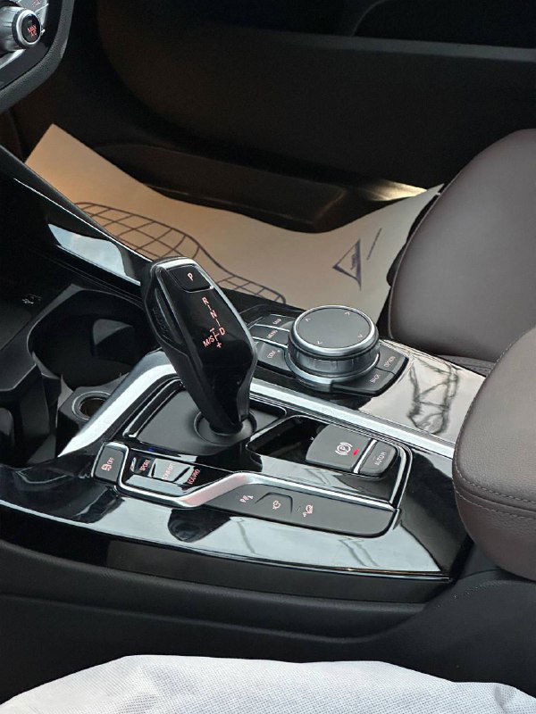 Центральная консоль BMW X3: селектор коробки передач, шайба управления iDrive и глянцевая отделка в зоне тоннеля между сиденьями.