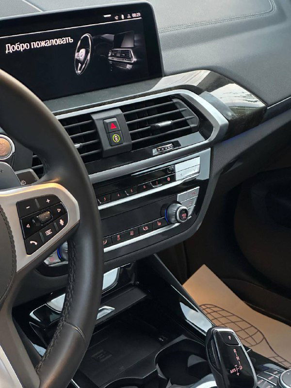Приборная панель и мультимедиа BMW X3: крупный экран, вентиляционные решётки и элементы управления климатом на передней панели.