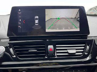 Дисплей мультимедиа BMW 1‑Series с активным изображением камеры заднего вида и траекторными линиями в паркинге; экран крупным планом.