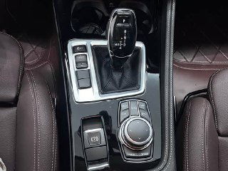 Центральная консоль BMW 1‑Series с селектором коробки, шайбой управления iDrive и рядом кнопок; видно качество отделки и элементы управления.