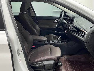 Передние сиденья BMW 1‑Series, вид под углом: коричневая кожаная отделка, подлокотник и пространство водителя с открытой дверью.