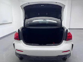 Открытый багажник BMW 1‑Series, вид внутрь грузового отсека; на фото видно объём багажника и заднюю часть автомобиля в шоуруме.