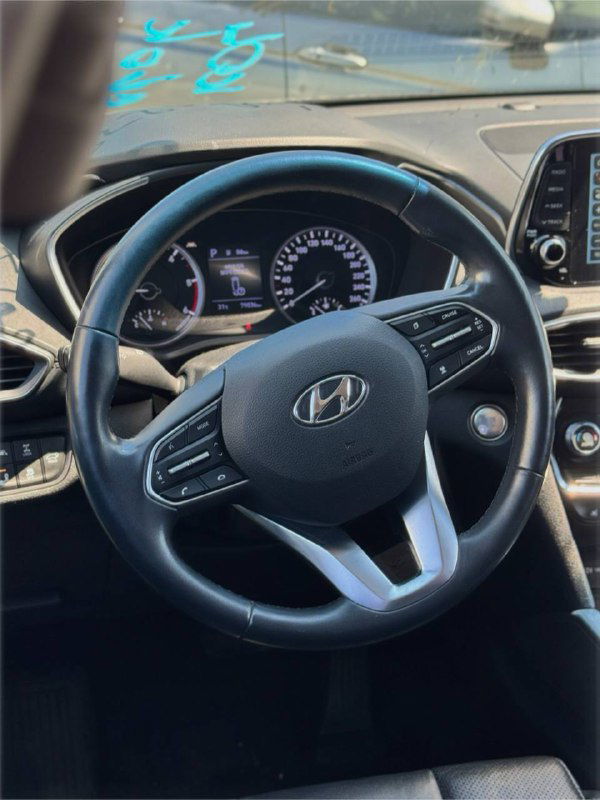 Руль и панель приборов Hyundai Santa Fe 2019: крупный план руля, спидометр и тахометр, состояние салона видно ясно на фото.