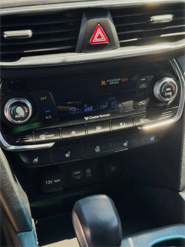 Ближний план панели климат-контроля и кнопок управления в салоне Hyundai Santa Fe; видно режимы и интерфейс регулировки температуры.