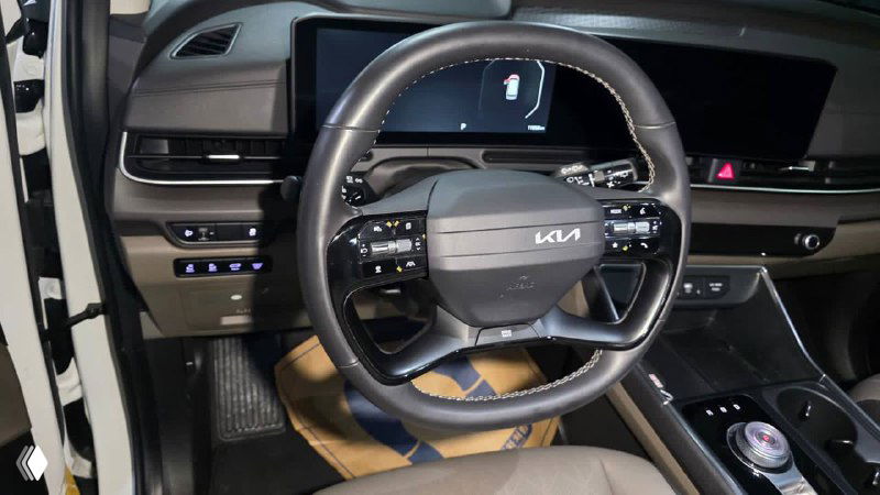 Салон KIA Carnival 2024: передняя панель и рулевое колесо KIA, крупный план приборной панели и центрального дисплея в подготовленном автомобиле.