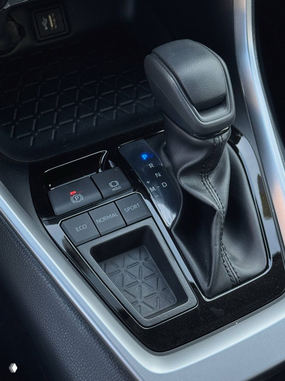 Крупный план рычага селектора вариатора и блока режимов движения (ECO, NORMAL, SPORT), вид на прихват центральной консоли и емкость для мелочей.