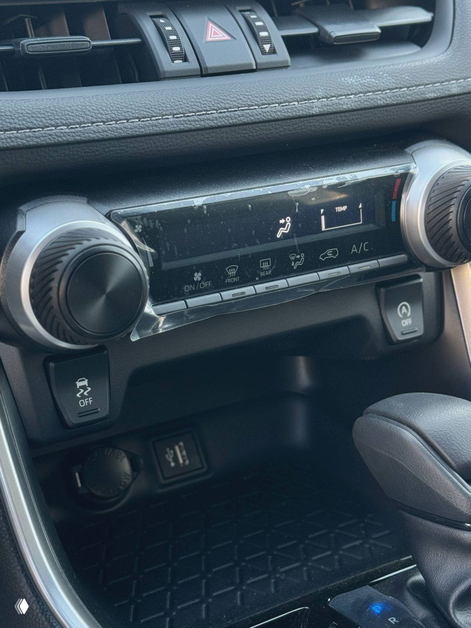 Панель управления климат-контролем и отделение под центральной консолью, защитная плёнка на элементах отделки, вид крупным планом.