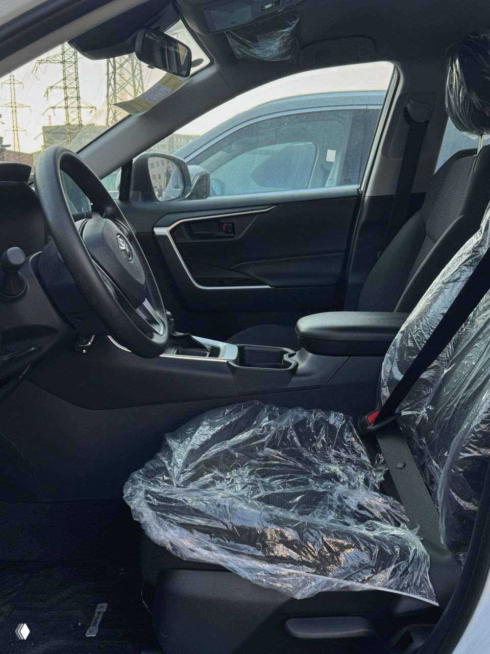 Вид на переднее пассажирское сиденье и дверь изнутри: плёнка на сиденьях, подлокотник, общий вид салона спереди, новая обивка.