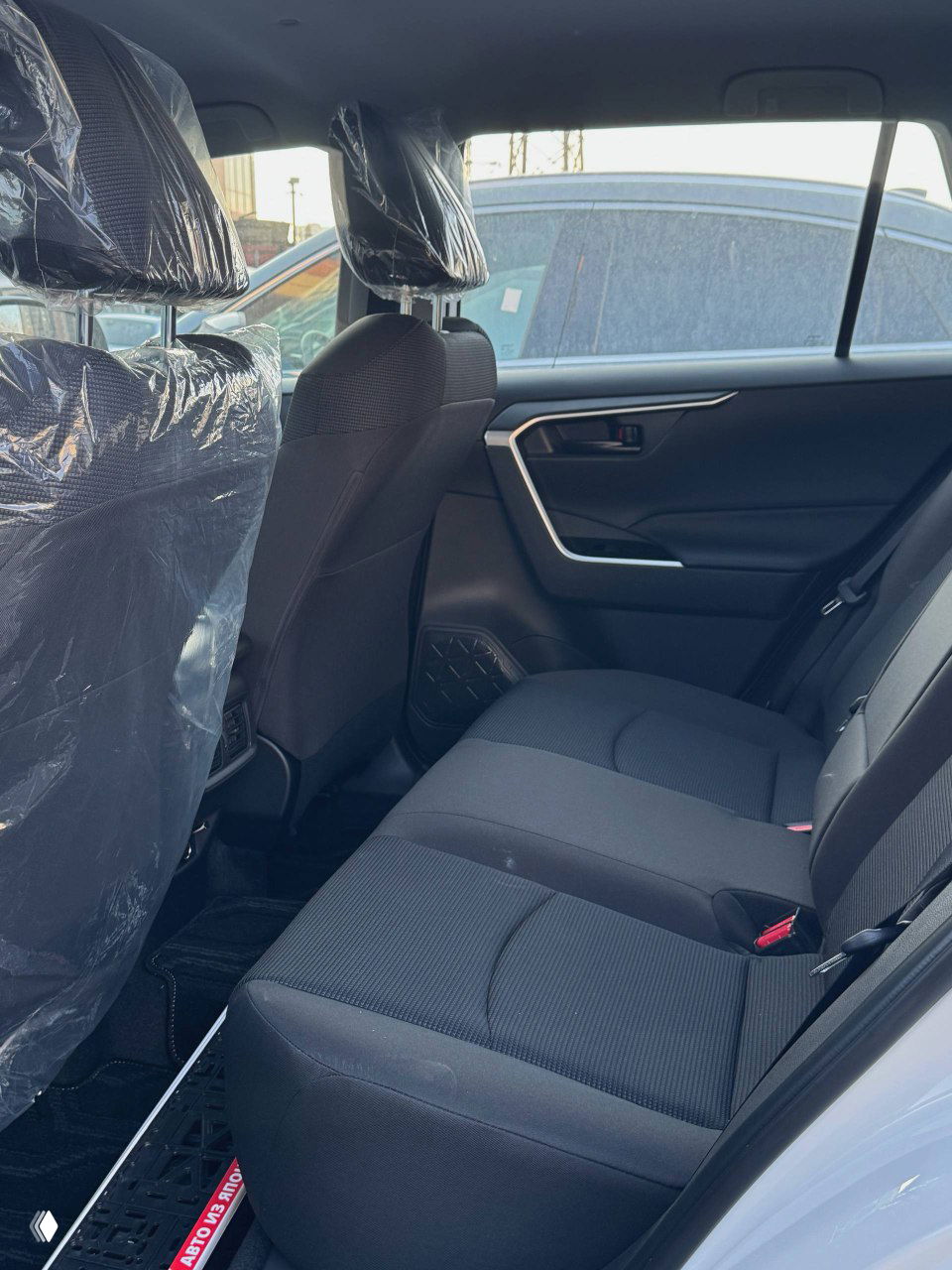 Вид на задний ряд сидений Toyota RAV4 внутри салона, тканевая обивка, пространство для пассажиров, чистое состояние, новый автомобиль.