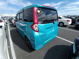 Фотография сзади бирюзовой Toyota Roomy 2022 на ярде порта: вид задней двери, фонарей и емкости багажного отсека на парковке.