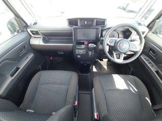 Вид на переднюю часть салона Toyota Roomy 2022: рулевое колесо, мультимедийный экран, центральная консоль и оба передних сиденья.