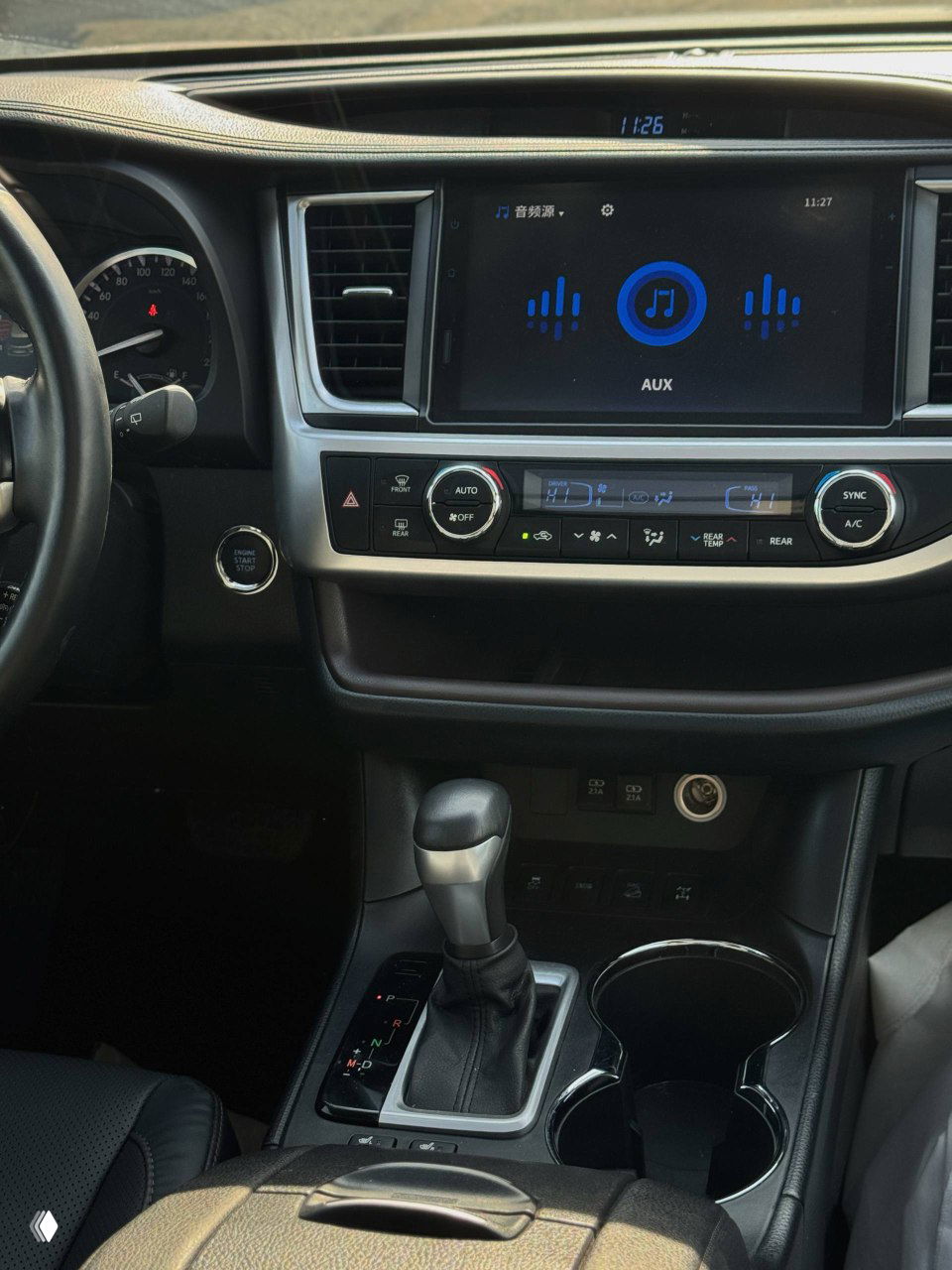 Центральная консоль Toyota Highlander с мультимедийным экраном, климат-контролем и селектором АКПП, видно состояние панели и интерфейса AUX.