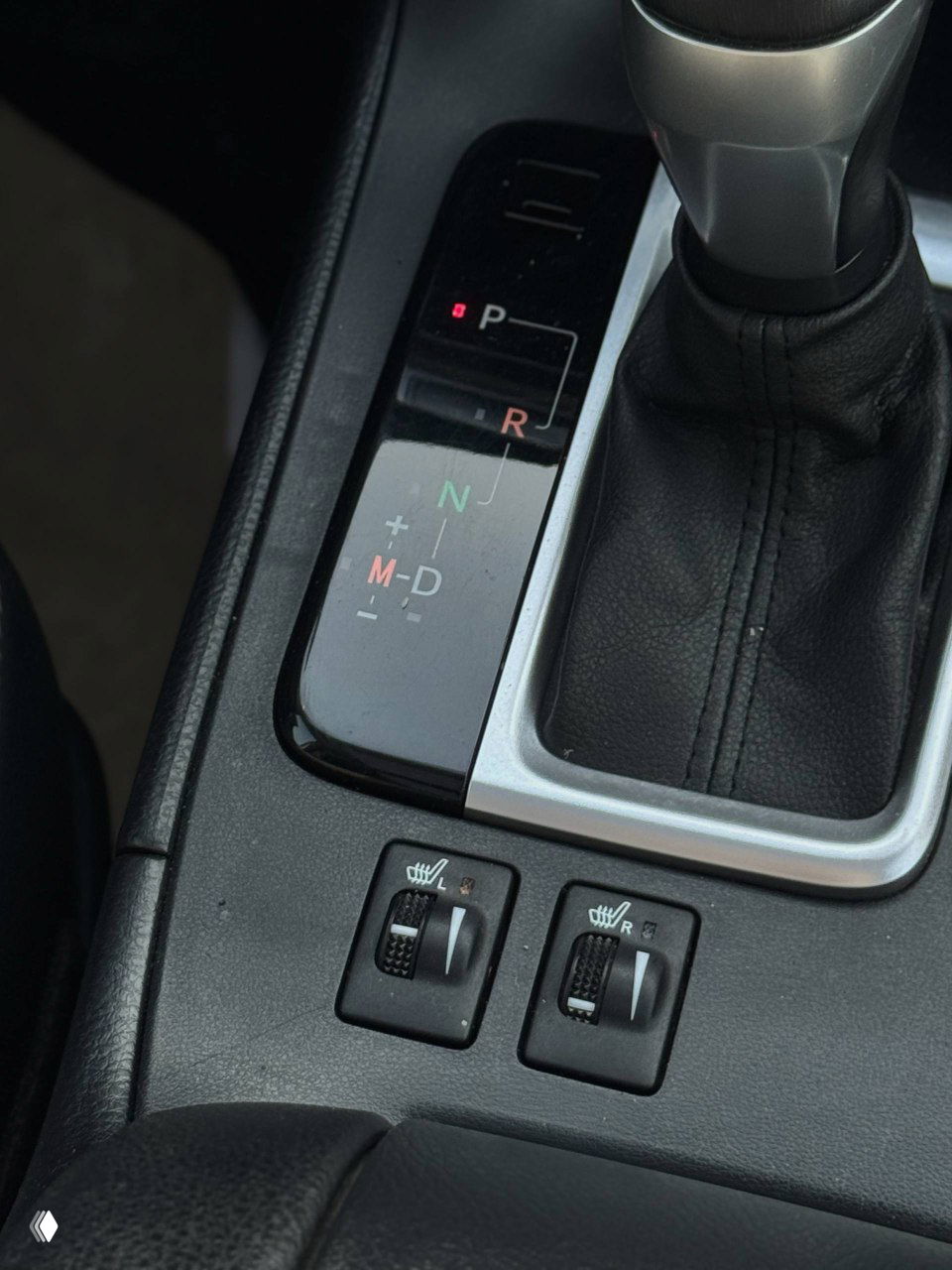 Крупный план селектора передач и блока управления обогревом сидений Toyota Highlander, вид элементов привода, индикаторы P R N D и режим M-D.