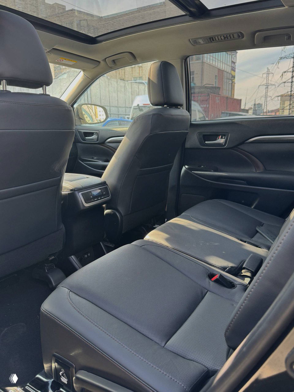 Вид на задний ряд сидений Toyota Highlander: чёрная обшивка, пространство для пассажиров и центральный пульт управления климатом для задних сидений.