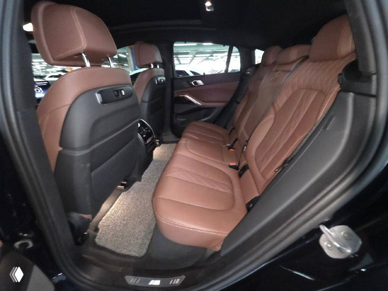 Задний ряд сидений BMW X6 2024: коричневые кожаные кресла, пространство для пассажиров и дверные панели с отделкой.