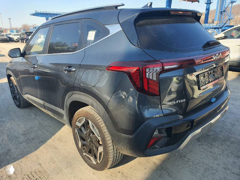 Задний трёхчетвертной вид KIA Seltos 2022: багажник, фонари и форма кормы кузова, автомобиль стоит на площадке портовой стоянки.