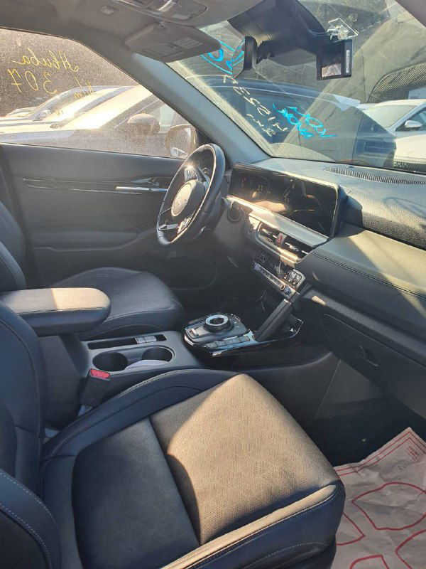 Интерьер KIA Seltos 2022 — передняя панель, мультимедийный экран, руль и передние сиденья, съёмка с пассажирской стороны при дневном свете.