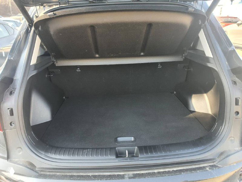 Открытый багажник KIA Seltos 2022: объём грузового отсека, ровное напольное покрытие и боковые ниши без вещей, снимок со стороны задней двери.