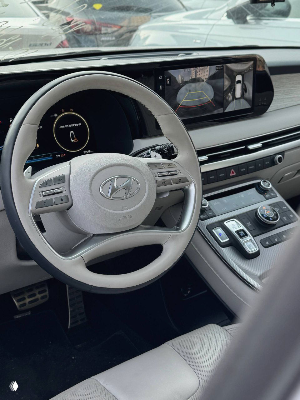 Руль и центральная консоль Hyundai Palisade Calligraphy: крупный план руля, экран парковки и элементы управления на передней панели.