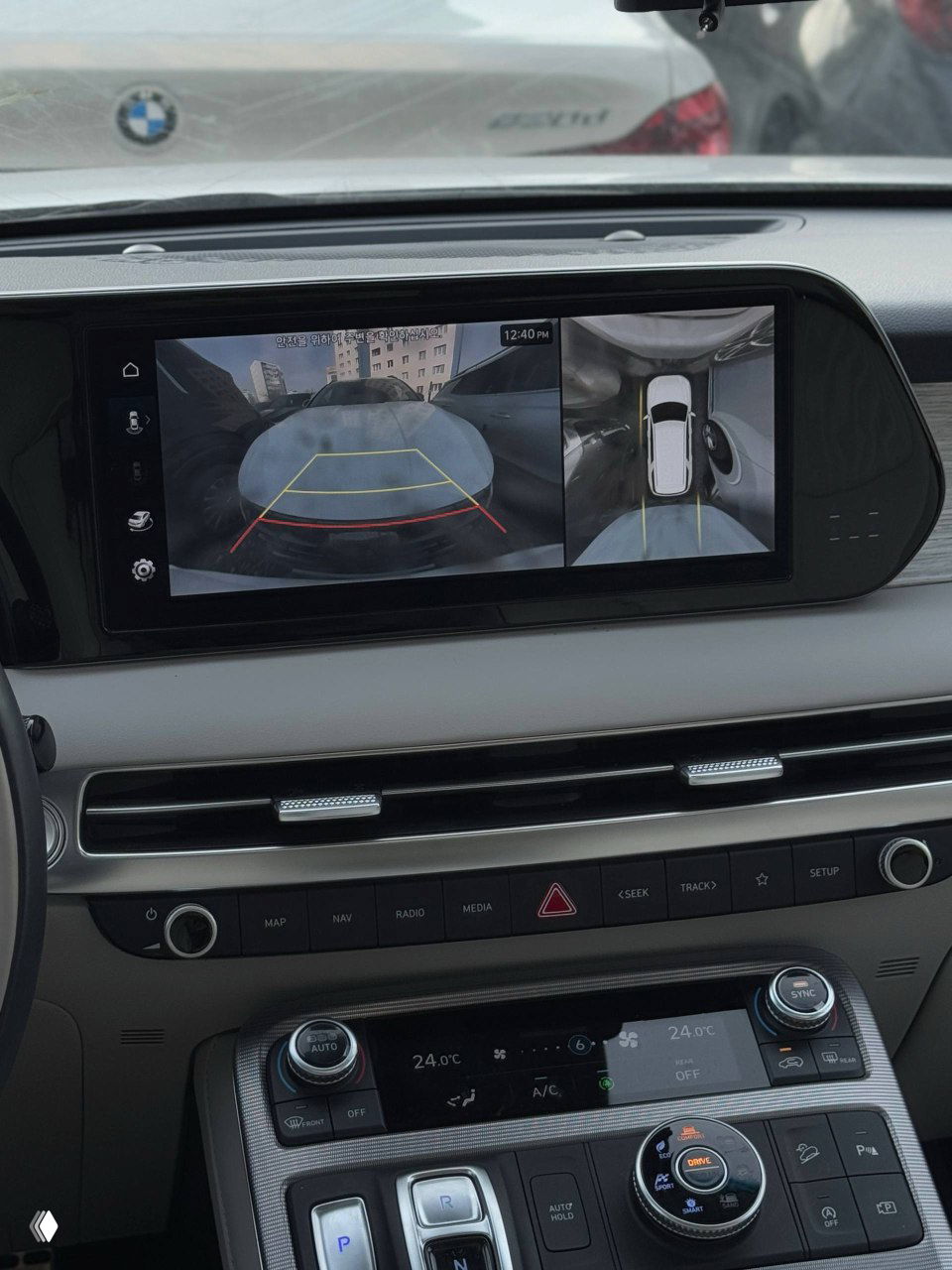 Крупный план центрального дисплея с изображением камеры заднего вида и обзором парковочной ситуации рядом с автомобилем.