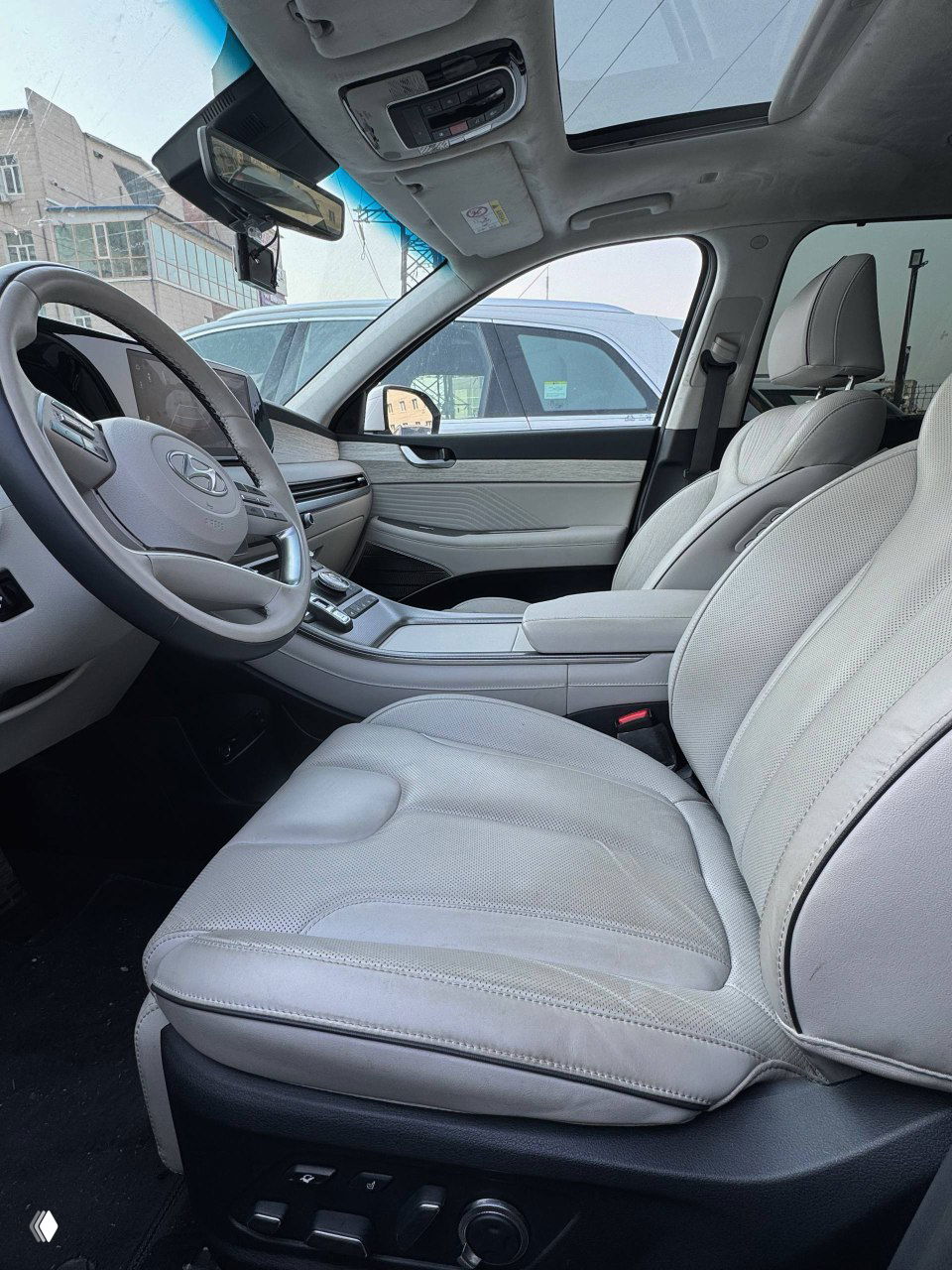 Вид пассажирской части салона с переднего сиденья: светлая отделка, сиденья и подлокотник, демонстрация общего состояния интерьера.