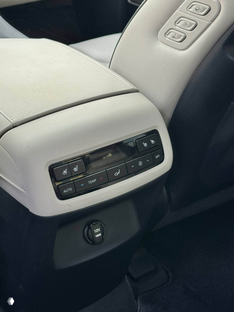 Крупный план блока управления климатом для задних пассажиров и розетки 12V, показывающий дополнительные опции салона автомобиля.